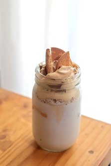Creamy iced coffee topped with whipped coffee and cookies in a mason jar, a trendy cafe-style beverage.
